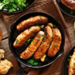 Tasty fried sausages in frying pan over wooden background. Top view, flat lay
