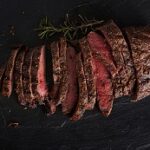 grilled flat iron steak shot in flat lay style from overhead on dark slate